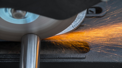 Cutting a metallic rod by a circular saw machine. Close-up of hot sparks when sawing a steel workpiece. Motion blur of disc with sharp blade. Idea of metal working in mechanical engineering.