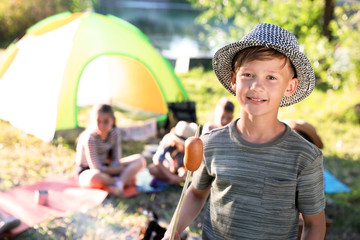 Wall Mural - little boy with fried sausage outdoors. summer camp