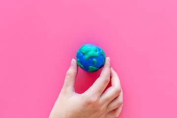 Wall Mural - Earth. Hand hold plastiline symbol of planet Earth globe on pink background top view copy space