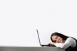 © spaskov - Beautiful brunette girl in glasses sits at a table and is sleeping on the computer, white background.