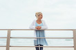Slender trendy blond woman on a waterfront pier