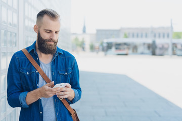 Bearded man reading a sms on his mobile phone