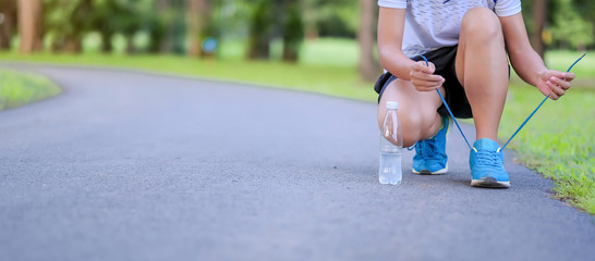 Young athlete woman tying running shoes in the park outdoor, female runner ready for jogging on the road outside, asian Fitness walking and exercise on footpath in morning. wellness and sport concepts