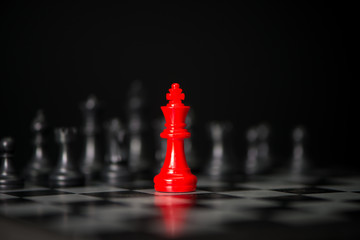 Red chess between black chess board game for competition and strategy, business success concept