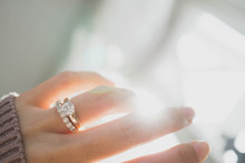 Close Up Of Elegant Diamond Ring On Woman Finger With Dark Pink Sweater Winter Clothe And Sunlight Tone. Love And Wedding Concept.soft And Selective Focus.
