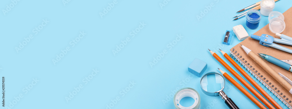 School stationary on blue background. Notebook, pens, pencils and other tools. Banner for website. - obrazy, fototapety, plakaty 