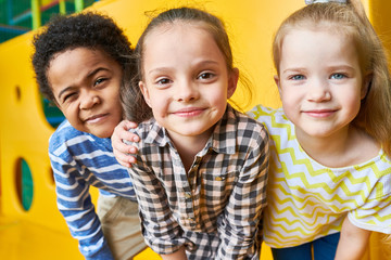 colorful portrait of three happy kids posing looking at camera while having fun playing in children 
