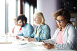 © pressmaster - Serious businesswoman concentrating on reading important document on background of colleagues