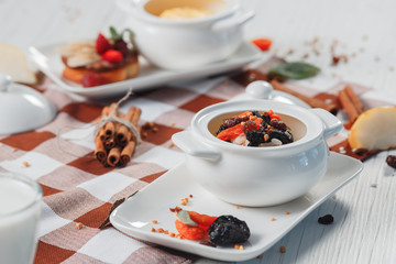 Bowl two of rice porridge with prunes, raisins on a rustic table, a hot and healthy breakfast meal, side view