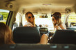 Three women enjoying road trip. They chatting while sitting in the car.