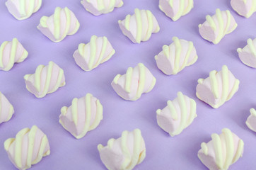 Colorful marshmallow laid out on violet paper background. pastel creative textured pattern. Perspective macro shot