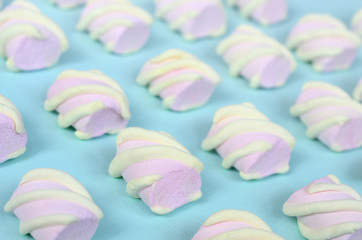 Colorful marshmallow laid out on blue paper background. pastel creative textured pattern. Perspective macro shot