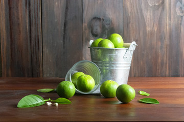 Canvas Print - Lime or green lemon tank and lime glass with leaf and blossom on wooden table.Sour fruit or raw food.