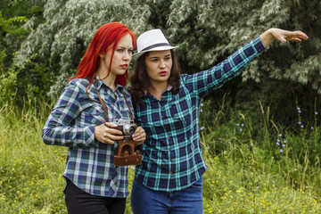 Two young girls with a camera are photographed and walking in the park