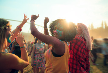 Wall Mural - Multiethnic girls covered in colorful powder dancing and celebrating summer holi festival