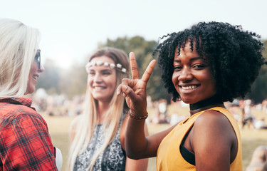 Friends having fun together outdoor at summer, beautiful black girl smiling and giving peace sign