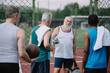 © LIGHTFIELD STUDIOS - selective focus of group of multiracial old sportsmen with basketball ball on playground
