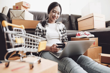 Shopaholic, Young woman holding credit card and using laptop computer at home. Online shopping concept