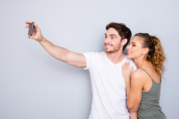 Poster - Technology gadget app internet online meeting concept. Portrait of joyful cheerful couple  shooting selfie on front camera of smartphone enjoying weekend together