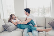 Portrait of funny comic spouses enjoying time together indoor laughing sitting on sofa in modern living room. Daydream mood inspiration concept