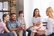 © LIGHTFIELD STUDIOS - happy family sitting on therapy session by female counselor writing in clipboard in office