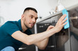 © Syda Productions - household and people concept - man wiping table with cloth cleaning oven door at home kitchen