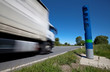 ein LKW passiert in schneller Fahrt eine blaue Maut-Säule an einer Bundesstraße in Deutschland