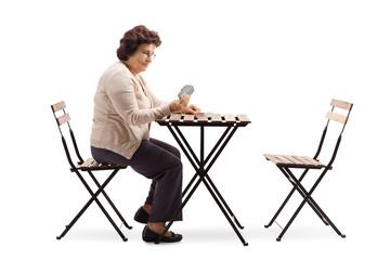 Poster - Senior lady sitting at a table and playing cards