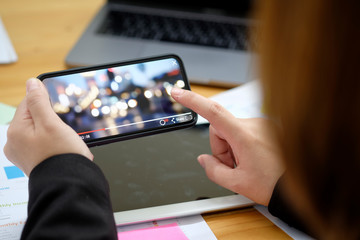 Wall Mural - Close up of women's hands holding mobile phone while play video from network in office.