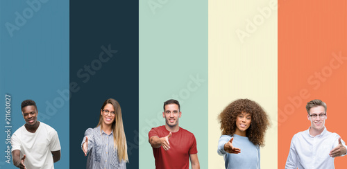 Cuadros en Lienzo Group of people over vintage colors background smiling friendly offering handshake as greeting and welcoming