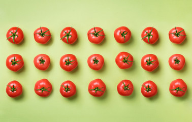 Wall Mural - creative pattern of red tomatos on green background. top view. copy space. minimal design. vegetaria