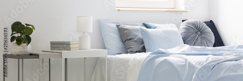 Cuadros en Lienzo Real photo of a bed with blue bedding and cushions standing next to white tables