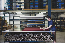 Male Cutting Fabric In A Manufacturing Warehouse