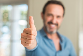 Handsome middle age man happy with big smile doing ok sign, thumb up with fingers, excellent sign