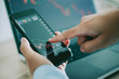 © chompoo - Business man point to the smart phone show financial market chart and Blurred background of a laptop show financial market chart, Stock market concept.