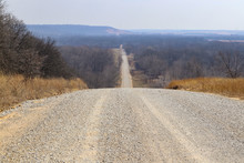 The Road Goes On Forever - Gravel Road In Winter Stretches Over Hills Almost To The Hazy Horizon