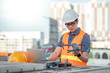 © zephyr_p - Young Asian man working with drone laptop and smartphone at construction site. Using unmanned aerial vehicle (UAV) for land and building site survey in civil engineering project.