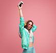 © kegfire - Young woman with smartphone dancing