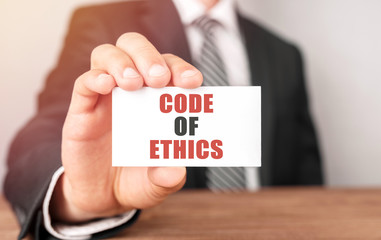 Poster - businessman holding a card with text code of ethics