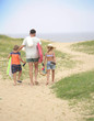 © goodluz - Family walking to the beach, sand dune path