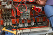 Electrical Engineer adjusts electrical equipment with a multimeter tester in his hand closeup