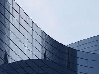 Poster - 3D stimulate of high rise curve glass building and dark steel window system on blue clear sky background,Business concept of future architecture,lookup to the angle of the corner building.3d rendering