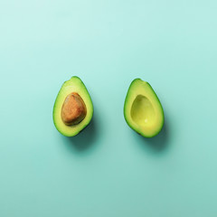 Wall Mural - green avocado halves with seed on blue pastel background. creative minimal flat lay style with copy 
