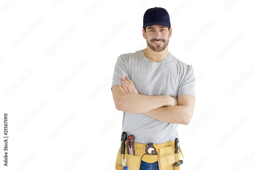 Portrait of young handyman standing at isolated white background with copy space. Successful repairman wearing baseball cap and tool belt. - obrazy, fototapety, plakaty 