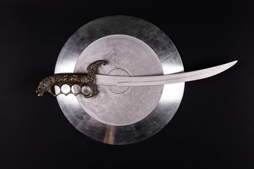 Poster - shiny metal shield and sword on a black isolated background