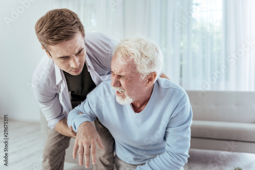 Fotomural Sudden dizziness. Kind man helping senior man who groaning