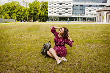 Wall Mural - A beautiful girl with a backpack poses near the university