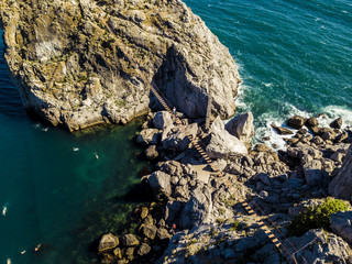 Poster - unrecognizable man walking on the rope bridge over the sea water aerial view