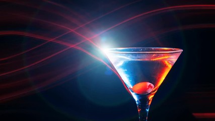 Wall Mural - Modern martini cocktail with yellow olive in the glass on dark background. Red light waves, bokeh and glare move on the frame. Entertainment and relaxation. Frozen in motion. Slow motion 4K Parallax