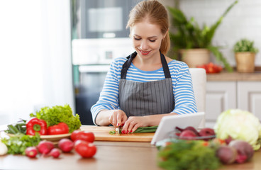 Wall Mural - happy woman preparing vegetable salad in kitchen